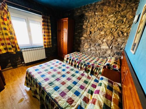 um quarto com uma cama e uma parede de pedra em Alojamiento La Milana em La Robla