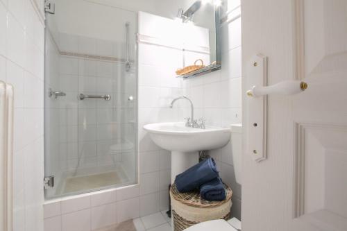 a white bathroom with a sink and a shower at Grand 3 Pièces Central et Calme in Menton