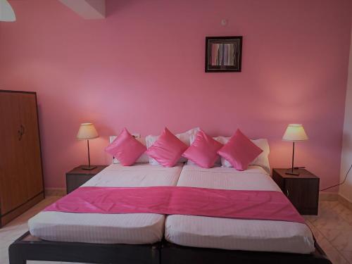 a bedroom with pink walls and a bed with pink pillows at TGF Dream Guest House in Majorda