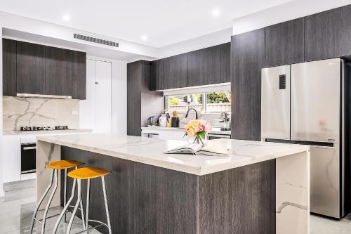 a kitchen with a large island with two stools at Blue Haven Retreat - Beverly Hills 208 in Sydney