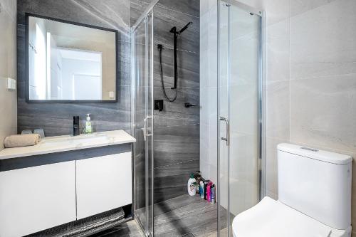 uma casa de banho com um chuveiro, um WC e um lavatório. em Spacious 4BR Villa with Office l Modern & Convenient em Sydney