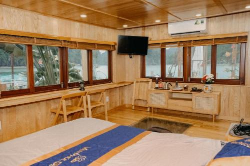 a room with a bed and a desk and a tv at Lan Ha Floating Homestay in Cat Ba