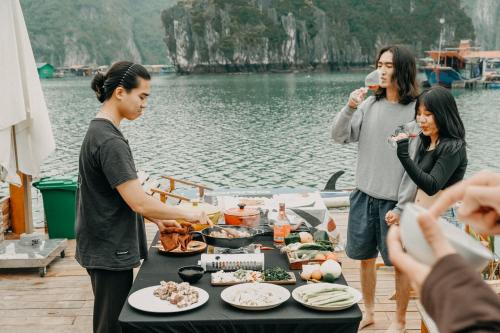a group of people standing around a table with food at Lan Ha Floating Homestay in Cat Ba