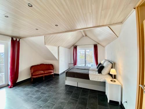 a bedroom with a bed and a red chair at Moderne Ferienwohnung Seeblick in Freudenberg