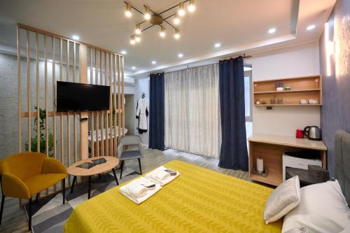 a bedroom with a yellow bed and a room with a tv at VANIMI lux apartmani in Kikinda