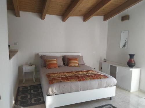 Dormitorio blanco con cama con almohadas de color naranja en Casa Ghirthalos, en Nuoro