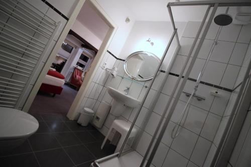 a bathroom with a shower and a sink and a mirror at Hotel Garni Zur Linde in Hitzacker