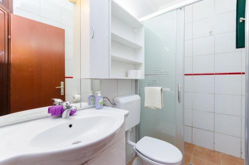 a white bathroom with a toilet and a sink at Gonar 300 Rab in Supetarska Draga