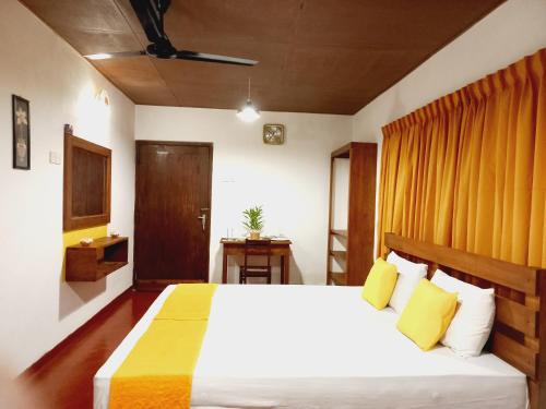 1 dormitorio con 1 cama blanca grande con almohadas amarillas en Coco Garden Villas 1 en Hikkaduwa