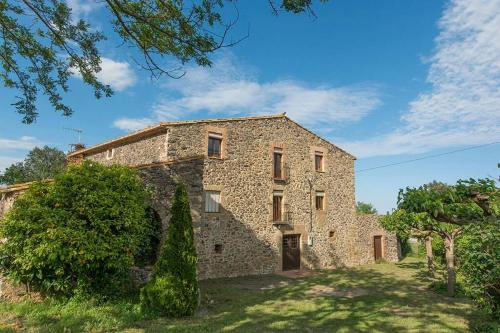 een groot stenen gebouw met bomen ervoor bij Casa Rural en Rupià con piscina in Rupiá