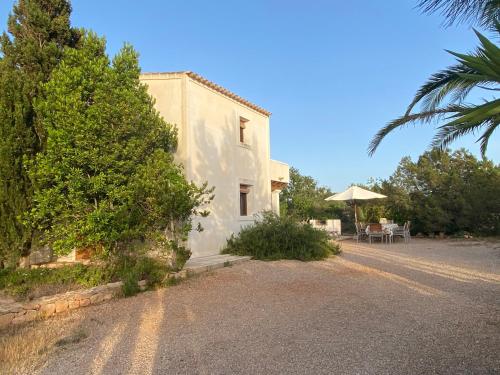 un edificio blanco con una mesa y una sombrilla en Ses Oliveres, en Cala Saona