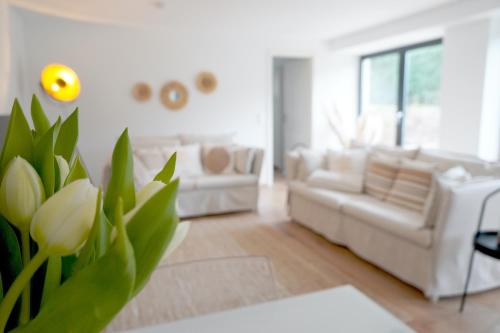 a living room with white furniture and a plant at Schwalbennest in Mechernich