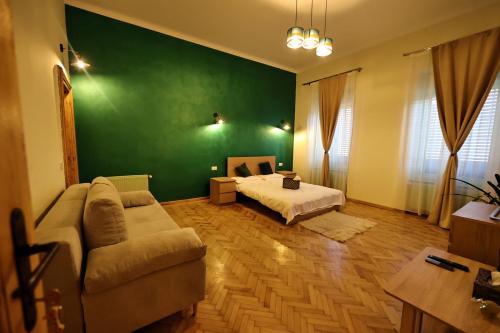 uma sala de estar com uma cama, um sofá e uma parede verde em Branko's Residence em Timisoara