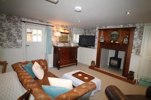 a living room with a leather couch and a fireplace at Mr Ralphs Cottage in Whitby