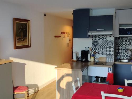 a kitchen with blue cabinets and a red table and chairs at Les Brasses in Viuz-en-Sallaz