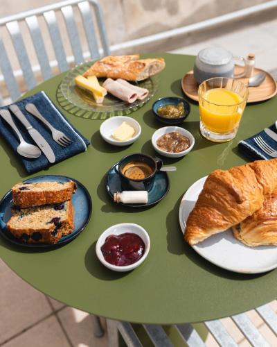 a green table with bread and other foods on it at Hôtel Rosalie in Paris
