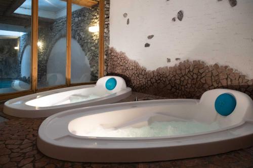 twee badkuipen in een kamer met een muur bij Hotel Helvetia in Livigno