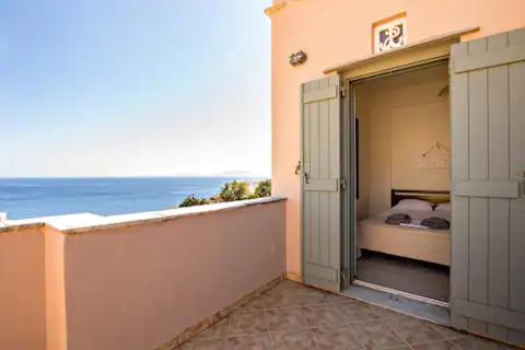 an open door to a bedroom with the ocean in the background at m.houses 2 in Agios Romanos