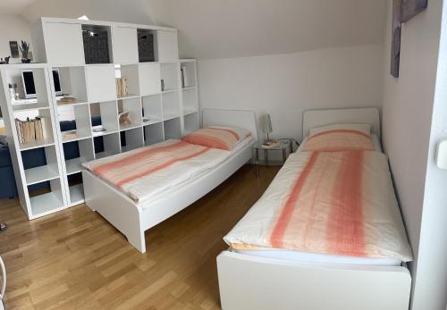 dwa łóżka w pokoju z białymi półkami w obiekcie Ferienwohnung „Anhaide“ w mieście Wörth am Rhein