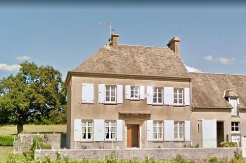 una grande casa con finestre bianche e tetto di Gîte spacieux et chaleureux a Sainte-Mère-Église