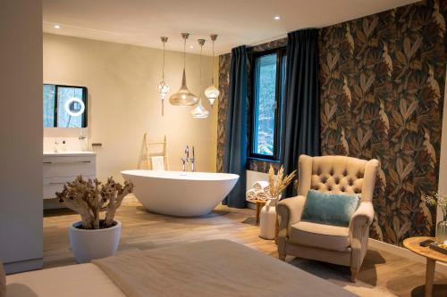 een badkamer met een bad, een stoel en een wastafel bij Boutique Hotel Bed&Bos in Best