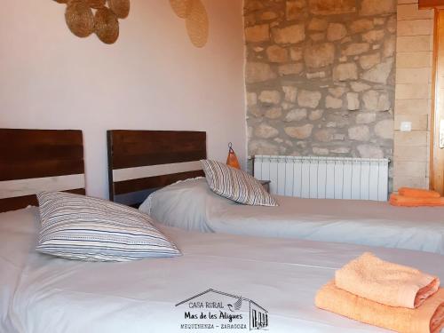 a bedroom with two beds and a stone wall at Casa Rural Mas de les Àligues in Mequinenza