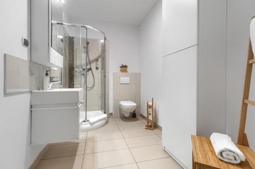 a white bathroom with a toilet and a sink at Aparthotel Platinum in Szczecin