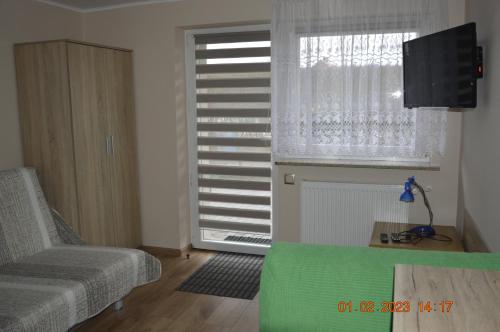 a living room with a chair and a window at Apartamenty i pokoje u Kryni in Sztutowo