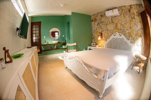 1 dormitorio con cama blanca y pared de piedra en Casa Nara, en Garopaba