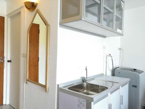 a small kitchen with a sink and a mirror at 7 pool condo opposite the train station near old city and Nimman in Chiang Mai