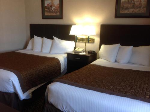 a hotel room with two beds and a lamp at Hawthorn Extended Stay by Wyndham El Paso in El Paso