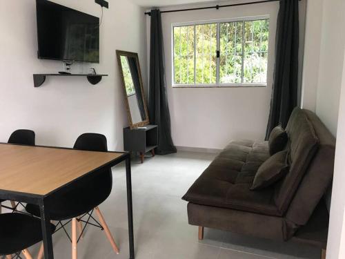 - un salon avec un canapé, une table et une fenêtre dans l'établissement Apartamentos Aconchegantes Bingen em Petrópolis, à Petrópolis