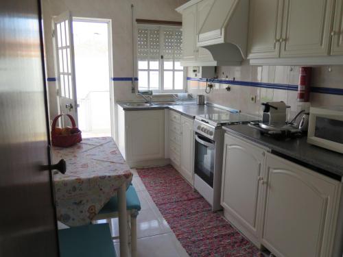 a kitchen with white cabinets and a sink and a table at Aveiro Luz in Aveiro