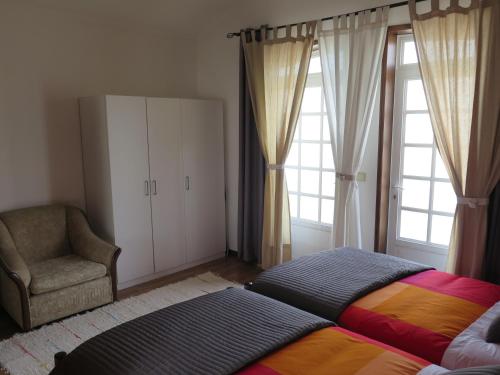 a bedroom with a bed and a chair and windows at Aveiro Luz in Aveiro
