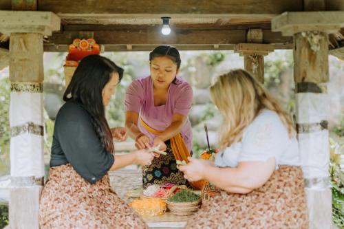 three women standing under a table with food at Dewangga Ubud in Ubud