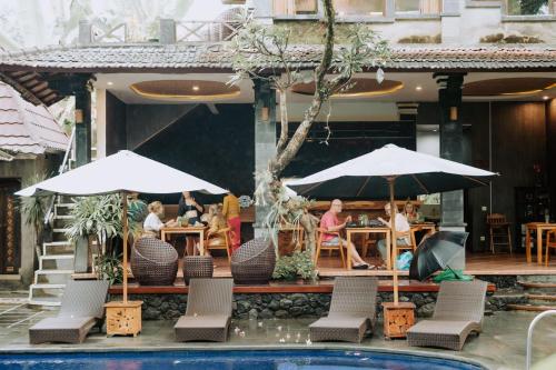 a group of people sitting at a restaurant with umbrellas at Dewangga Ubud in Ubud