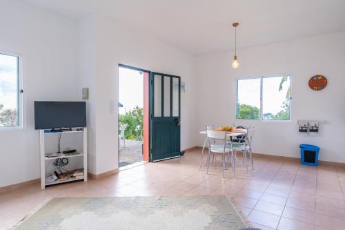 a living room with a table and a green door at Bungalows Do Amparo in Ponta do Pargo