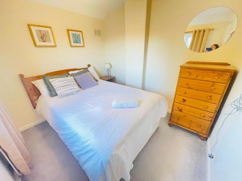 a bedroom with a bed and a mirror and a dresser at St Ives, King Bed Cosy home, parking, fast Wi Fi in St Ives