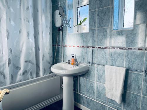 y baño de azulejos azules con lavabo y ducha. en St Ives, King Bed Cosy home, parking, fast Wi Fi en St Ives