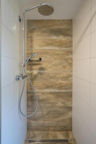 a shower in a bathroom with a wooden wall at AKORD chata in Námestovo