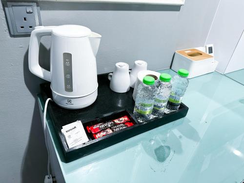 a counter with a coffee maker and bottles of water at 61 Hotel in Gua Musang
