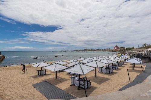a row of umbrellas on a beach with the ocean at Monte Estoril Train Station - Seaside Apartment in Estoril