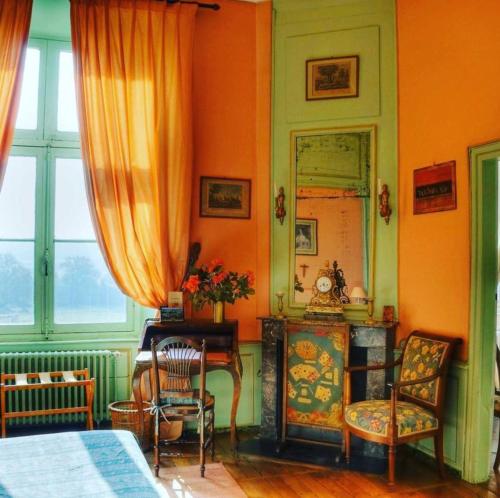 - une chambre dotée d'un mur orange avec un miroir et des chaises dans l'établissement Chateau du Fraisse, à Nouic