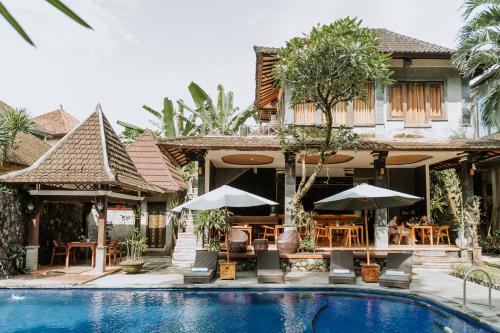 a resort with a swimming pool and tables and umbrellas at Dewangga Ubud in Ubud