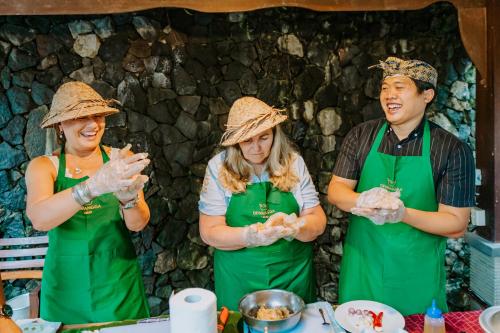 a group of three people in green aprons preparing food at Dewangga Ubud in Ubud
