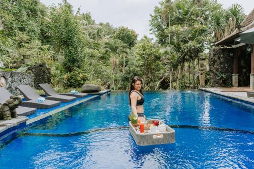 a woman standing in the water next to a swimming pool at Dewangga Ubud in Ubud