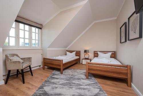 a attic bedroom with two beds and a chair at Seehof 34 in Bansin