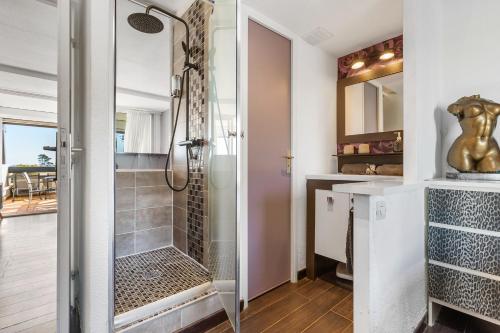 uma casa de banho com um chuveiro e uma porta de vidro em La vie en rose naturiste - Port Nature em Cap d'Agde