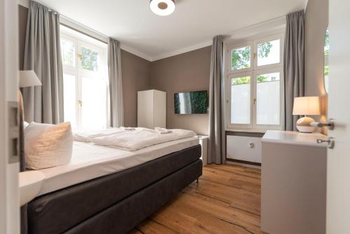 um quarto com uma cama grande e 2 janelas em Villa Doctores App 02 nur Erwachse em Heringsdorf