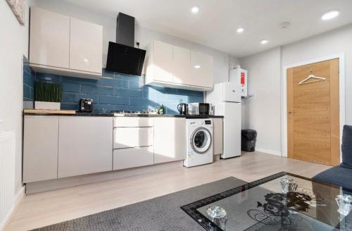 a kitchen with white cabinets and a washer and dryer at Luxury Flat in Moseley with Free Parking in Birmingham